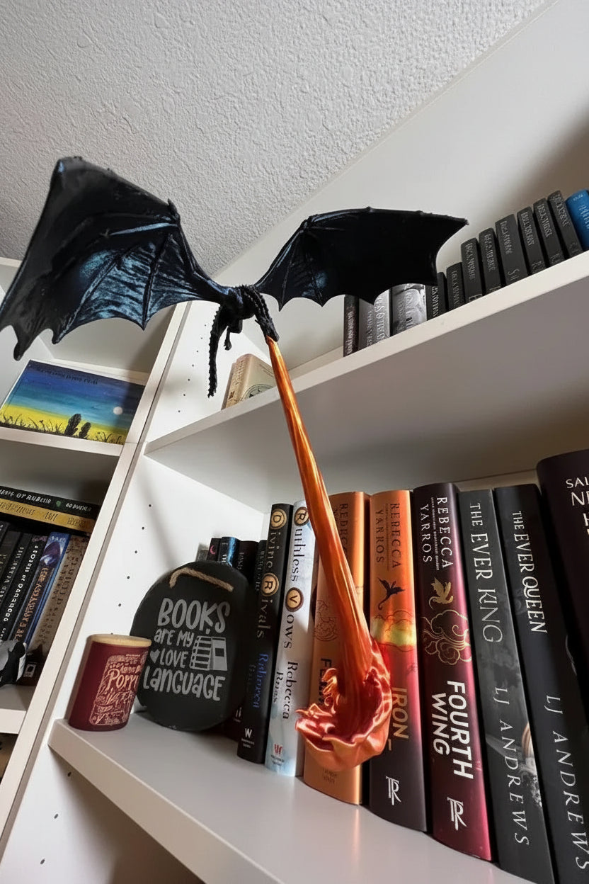 Dragon Flame Bookshelf Lamp perched on a shelf of fantasy romance books, breathing an orange flame